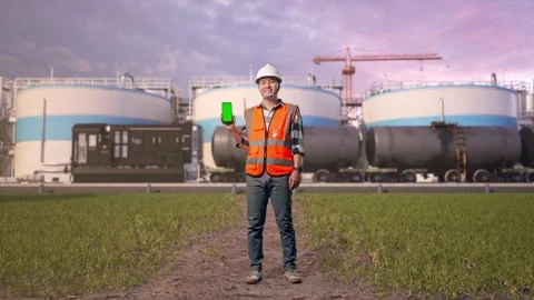Engineer Smiling And Showing Green Screen Smartphone at Oil Refinery Stock Footage 340142573