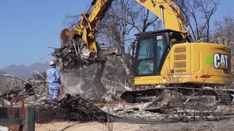 Engineer soaking smoldering debris for removal by machine at site      Stock Footage 300966251