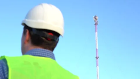 An engineer speaks on the phone against the backdrop of a telecom tower. Vídeo Stock 165670239