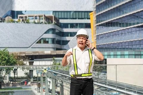 An engineer speaks on the phone with a tense expression at a construction s.. 스톡 사진