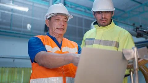 Engineer specialist checking and controlling machine in industrial factory Stock Photos