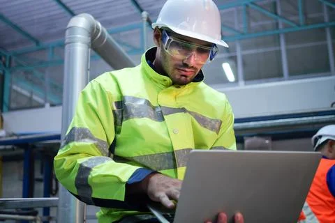 Engineer specialist using laptop checking and maintaining machine in factory 写真素材