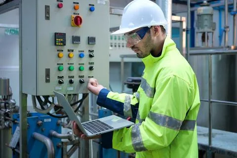 Engineer specialist using laptop checking and maintaining machine in factory Foto stock