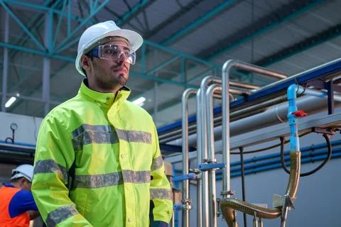 Engineer specialist using laptop checking and maintaining machine in factory Stock Photos
