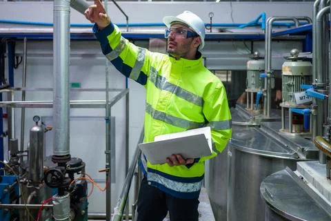 Engineer specialist using laptop checking and maintaining machine in factory Stock Photos