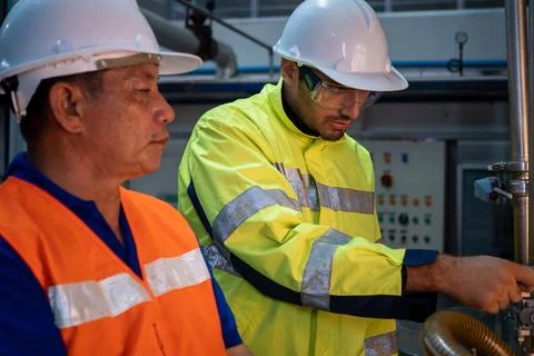 Engineer specialist using laptop checking and maintaining machine in factory Foto stock