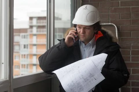 Engineer standing on the background of a new apartment building. House is built Stock Photos