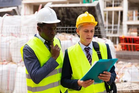 Engineer standing with builder supervising the construction process with house Stock Photos