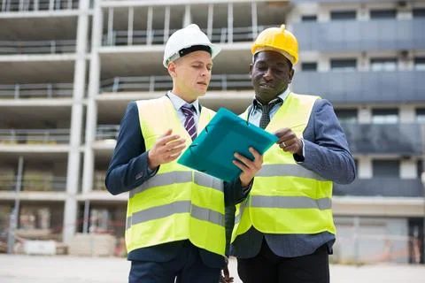 Engineer standing with builder supervising the construction process with house Stock Photos