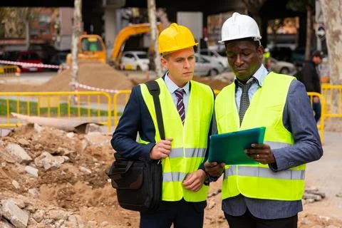 Engineer standing with builder supervising the construction process with house Stock Photos