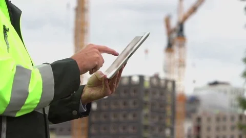 An engineer standing by a construction site, planning and looking at a tablet Stock Footage 80124916