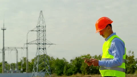 Engineer stands against power lines at transformer substation Stock Footage 166136700