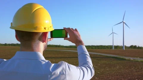The engineer stands on the background of windmills and takes pictures Video stock 76586288