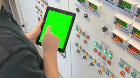 Engineer stands at the front of the control panel and holding a tablet with Stock Footage 61314609