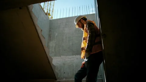 An engineer stands at the wall in the house inside the construction site Video stock 253594542