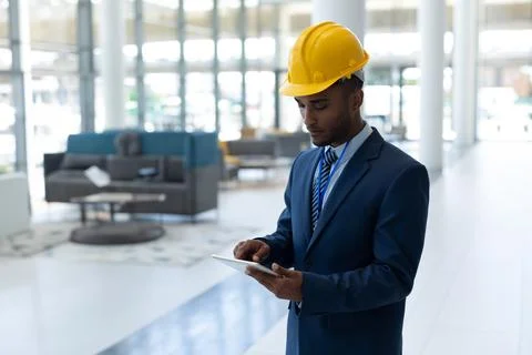 Engineer in suit using tablet in modern office building, focused on work, c.. Stock Photos