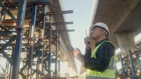 A engineer supervises road construction, commands with Walkie-Talkie radio .. Stock Footage 246350053