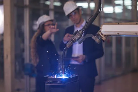 Engineer supervising autonomous producton process industry robot arm in facto 스톡 사진