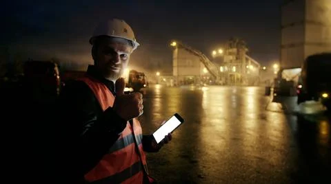 Engineer with tablet computer look at camera showing thumbup outdoors Foto stock