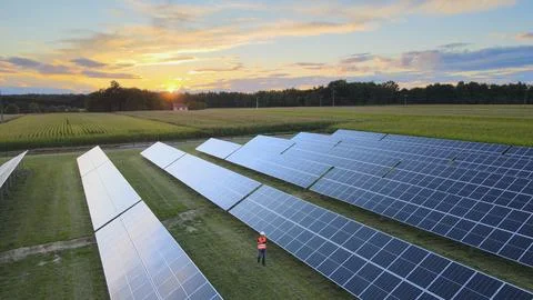 Engineer with tablet inspecting the solar panels on the fields at sunset Stock Photos