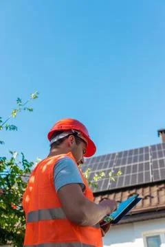Engineer with Tablet Inspecting Solar Panels on Roof Stock Photos