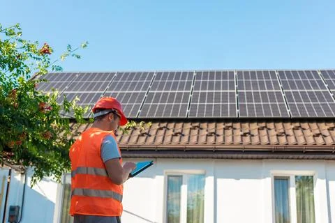 Engineer with Tablet Inspecting Solar Panels on Roof Foto stock