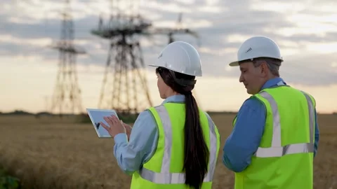 Engineer with tablet presents power plant project to manager walking along field Stock Footage 252647106