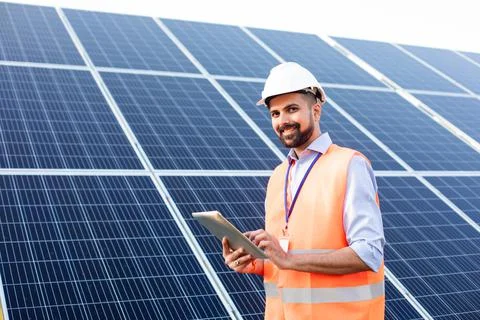 Engineer with a tablet stands on the background of a solar station Stock Photos