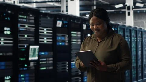 Engineer with tablet walks through data center server rows 写真素材