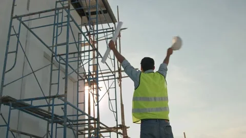 Engineer take of helmet and holding blueprint waving hand Stock Footage 146027417