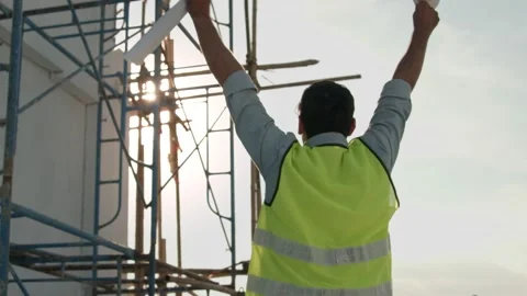 Engineer take of helmet and holding blueprint waving hand on rooftop Stock Footage 146681007