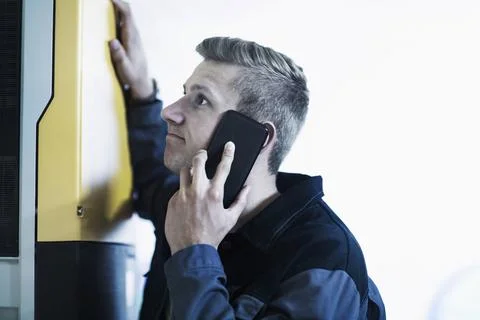 Engineer talking on mobile phone in workshop, Freiburg Im Breisgau, Baden-württe Foto stock