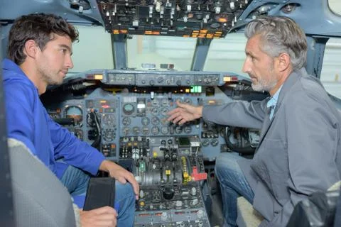 Engineer talking to trainee in cockpit of aircraft Stock Photos