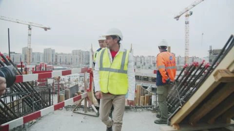 Engineer with taskmaster walks along sports arena building Stock Footage 228227034