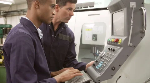 Engineer Teaching Apprentice To Use Computerized Lathe Stock Footage 40246869