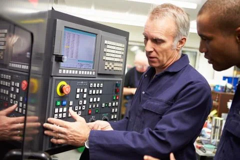 Engineer teaching apprentice to use computerized lathe 스톡 사진