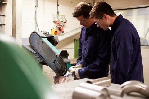 Engineer teaching apprentice to use grinding machine 库存照片