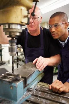 Engineer teaching apprentice to use milling machine Stock Photos