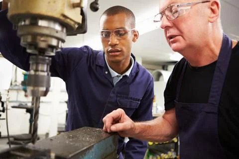 Engineer teaching apprentice to use milling machine Stock Photos