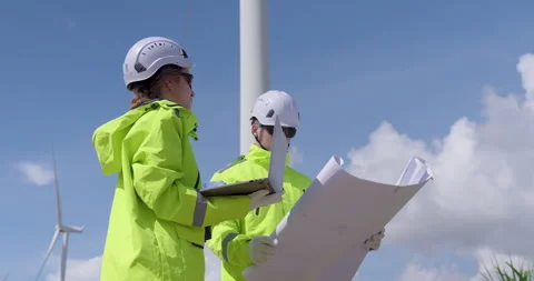 Engineer team reviewing plan near wind turbine field checking progress of 動画素材 325842172