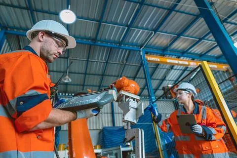 Engineer team service programming automated robotic welding arm in modern h.. Stock Photos