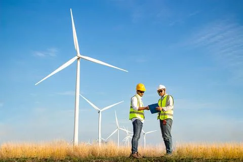 Engineer team working in wind turbine farm. Renewable energy with wind genera Stock Photos