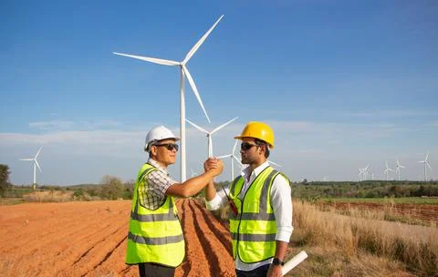 Engineer team working in wind turbine farm. Renewable energy with wind genera Stock Photos