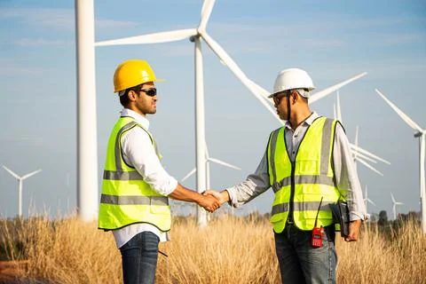 Engineer team working in wind turbine farm. Renewable energy with wind genera Stock Photos