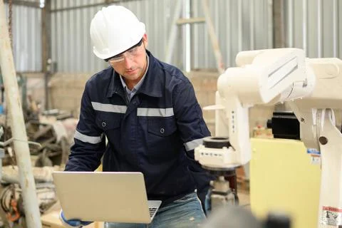 Engineer technician controlling robotic arms on computer laptop Stock Photos