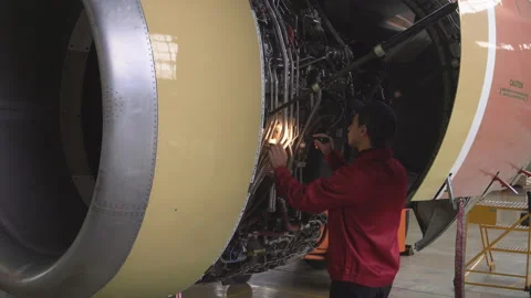Engineer, technician examines the jet engine with a flashlight. Stock Footage 98003011