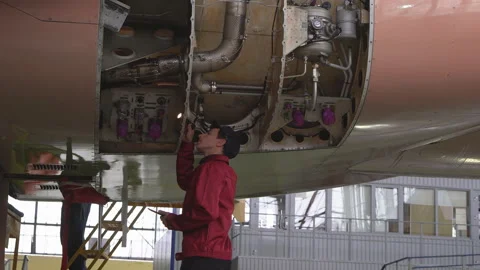 Engineer, technician examines the jet engine with a flashlight. Stock Footage 98006067