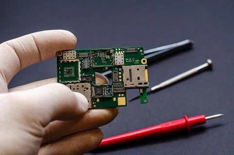 An engineer technician holds a chip and tools for repairing electronic gadget Stock Photos
