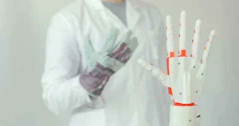 Engineer is testing robotic prosthesis hand which repeats the movement of his Stock Footage 106220943
