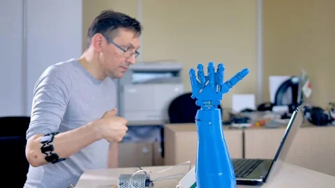 An engineer tests a blue robotic hand. Stock Footage 76773809
